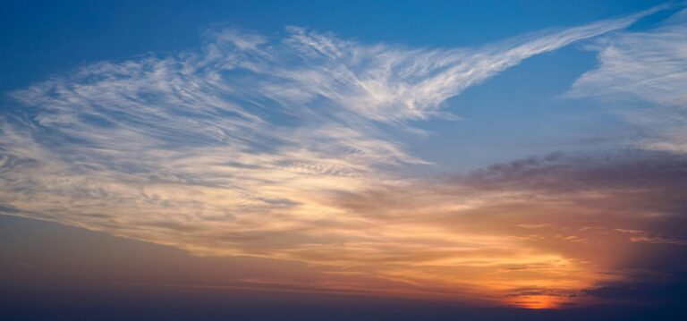 Breathtaking view of a sunset over the ocean, featuring vibrant colors and wispy clouds.